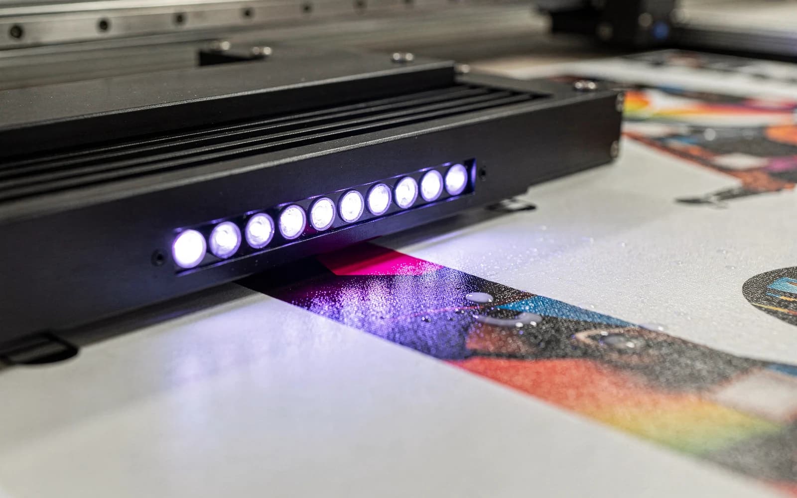 A UV-LED lamp curing freshly printed ink on a sheet, the cured area matte beside it