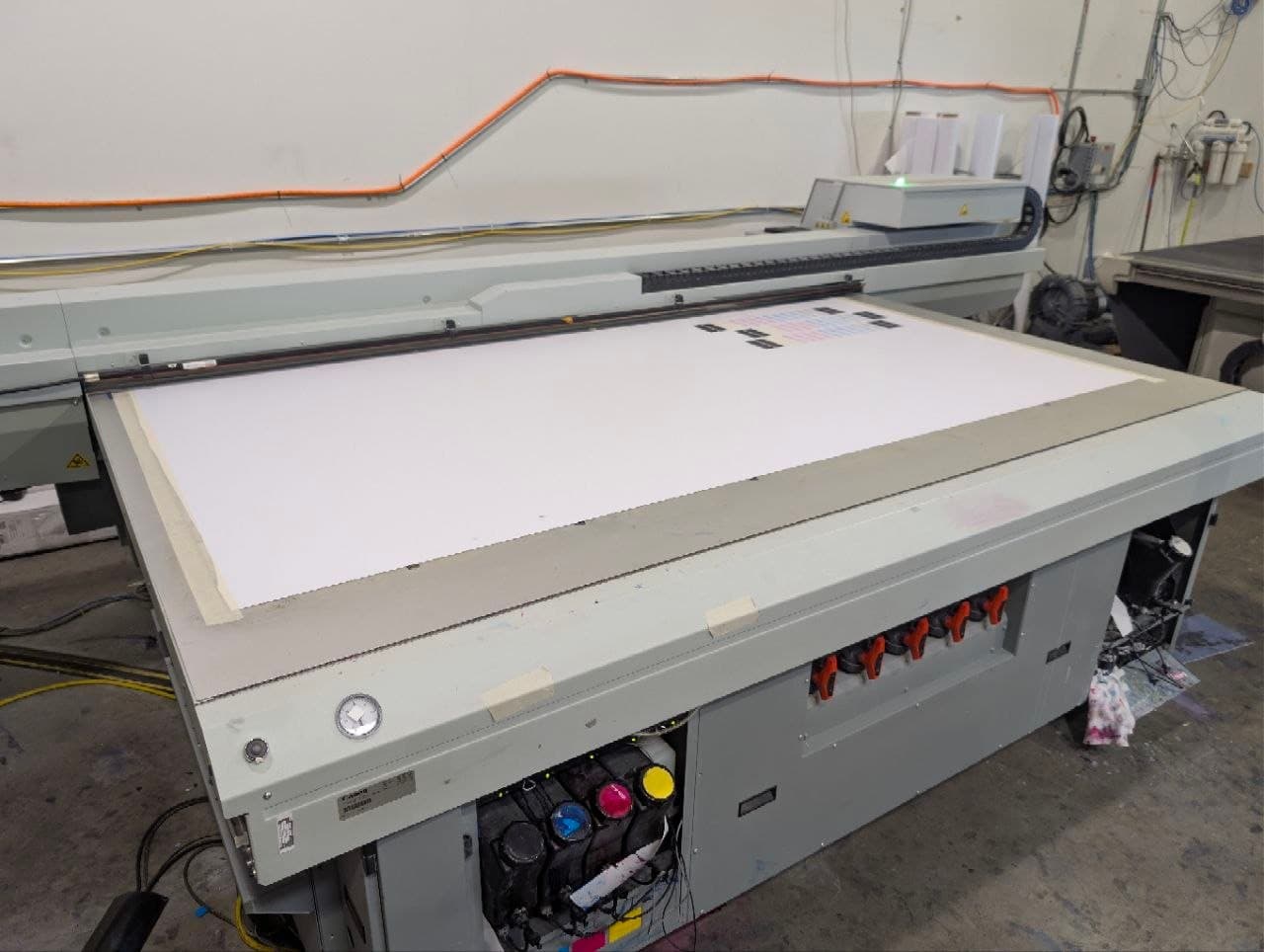 Océ Arizona 2280 with a blank sheet on the vacuum bed, ink tanks visible in the open cabinet